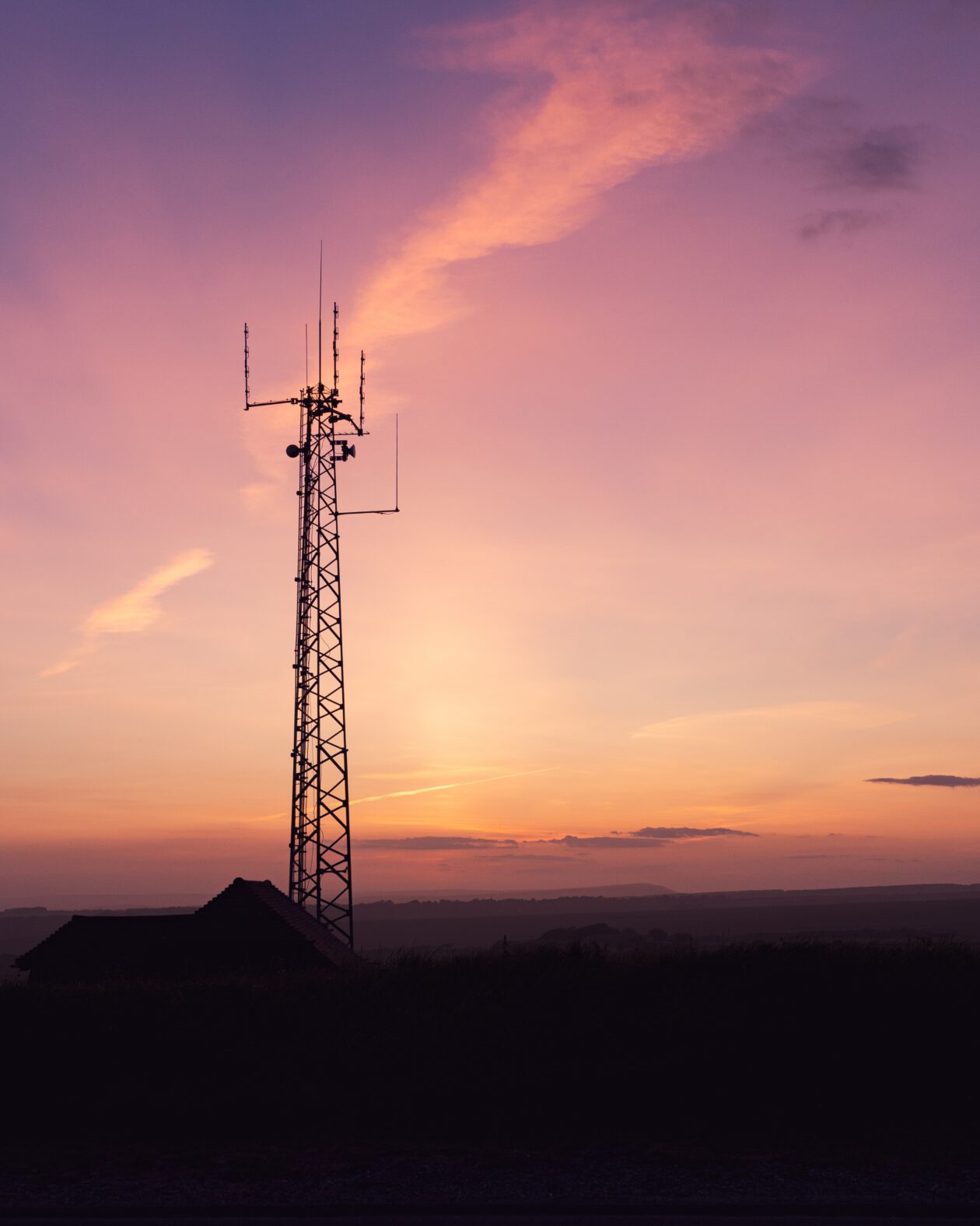 Vertical shot of a telecom tower in a field under the breathtaking sky -perfect for wallpaper